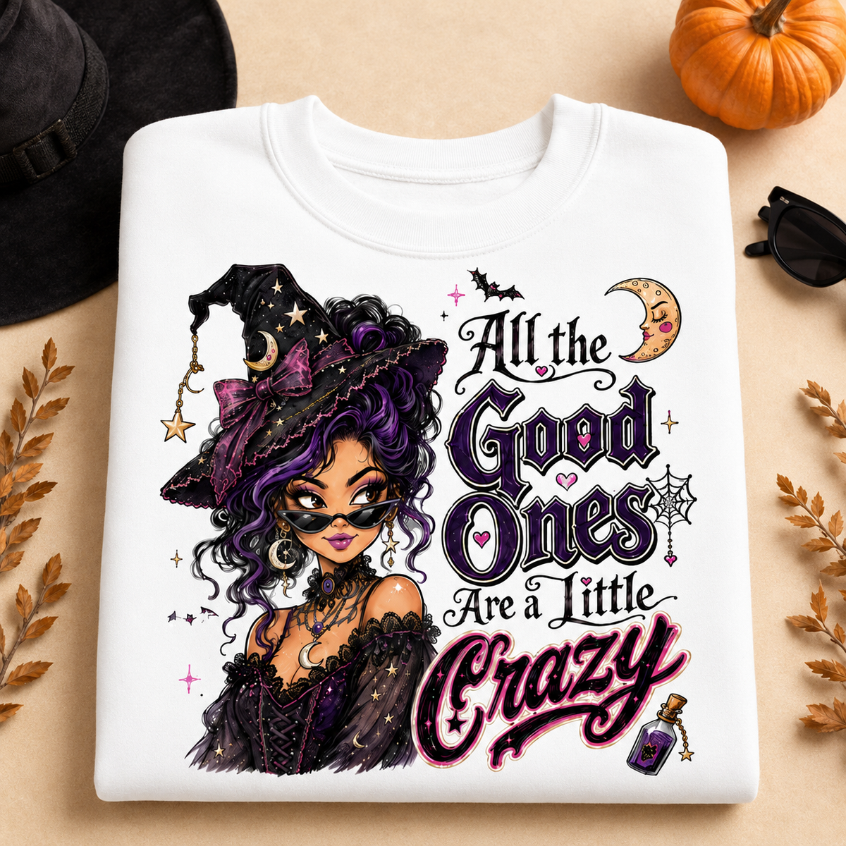 White Halloween witch sweatshirt laid flat with the “All the Good Ones Are a Little Crazy” graphic, featuring a purple-haired witch, crescent moon, bats, spiderweb, stars, and potion details.
