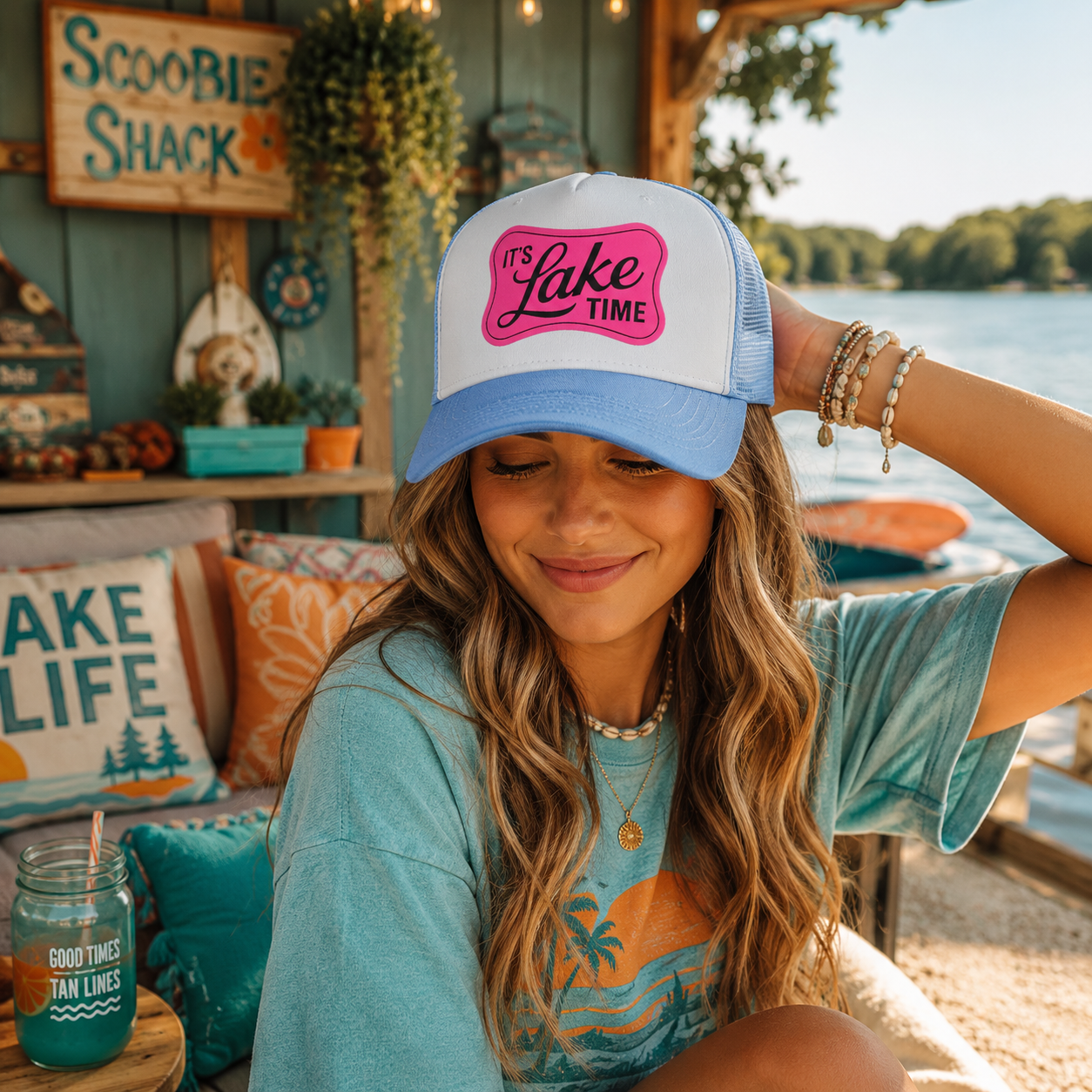 Woman wearing a 'It's Lake Time' cap by a lakeside cabin.