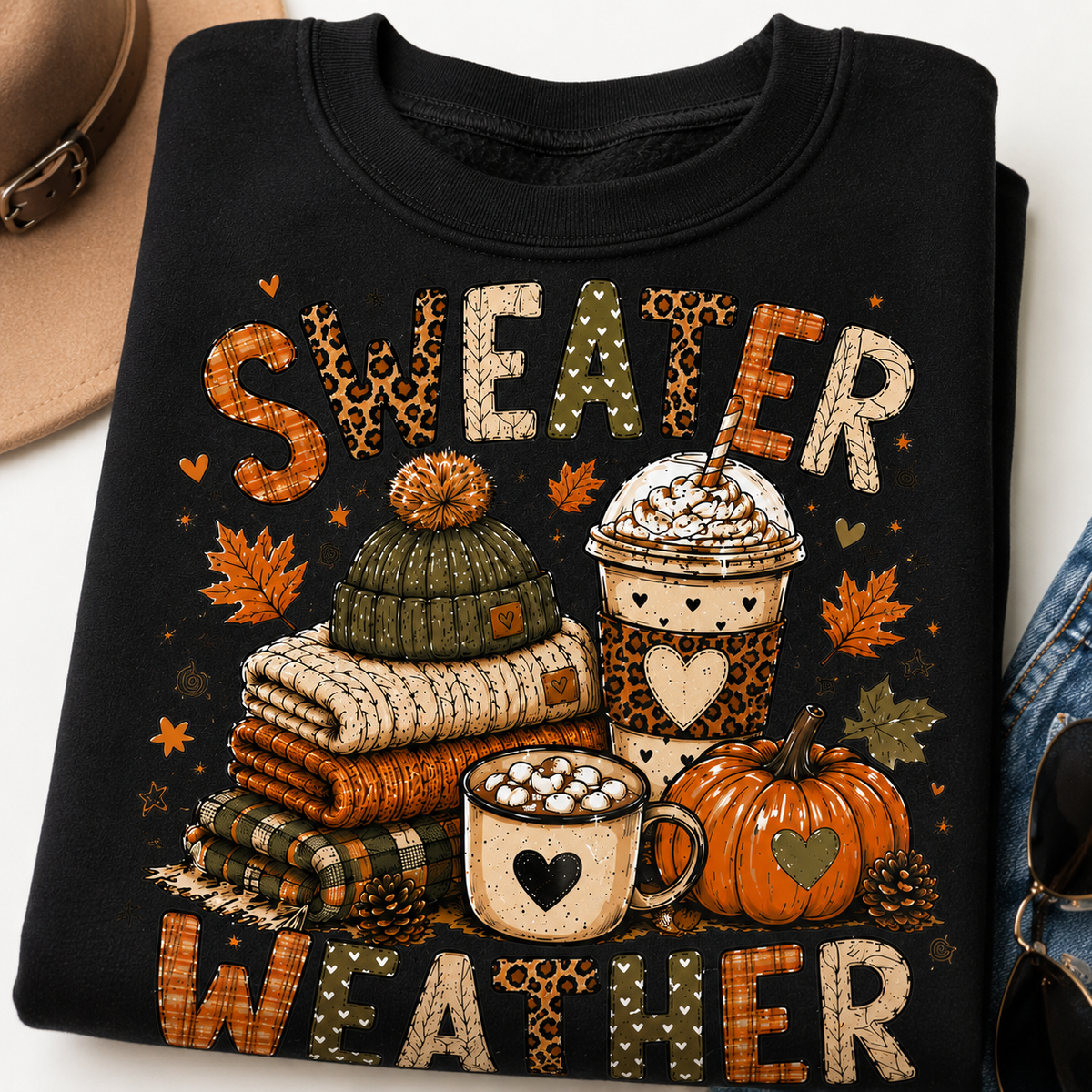 Folded black Sweater Weather sweatshirt with fall graphic featuring cozy sweaters, coffee drinks, pumpkin and autumn leaves