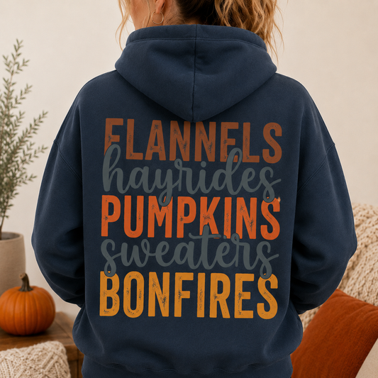 Woman wearing a Blue Dusk fall hoodie with Flannels, Hayrides, Pumpkins, Sweaters and Bonfires graphic on the back.