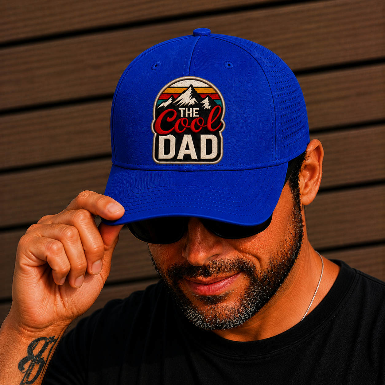 Man wearing a blue cap with 'The Cool Dad' logo against a wooden background