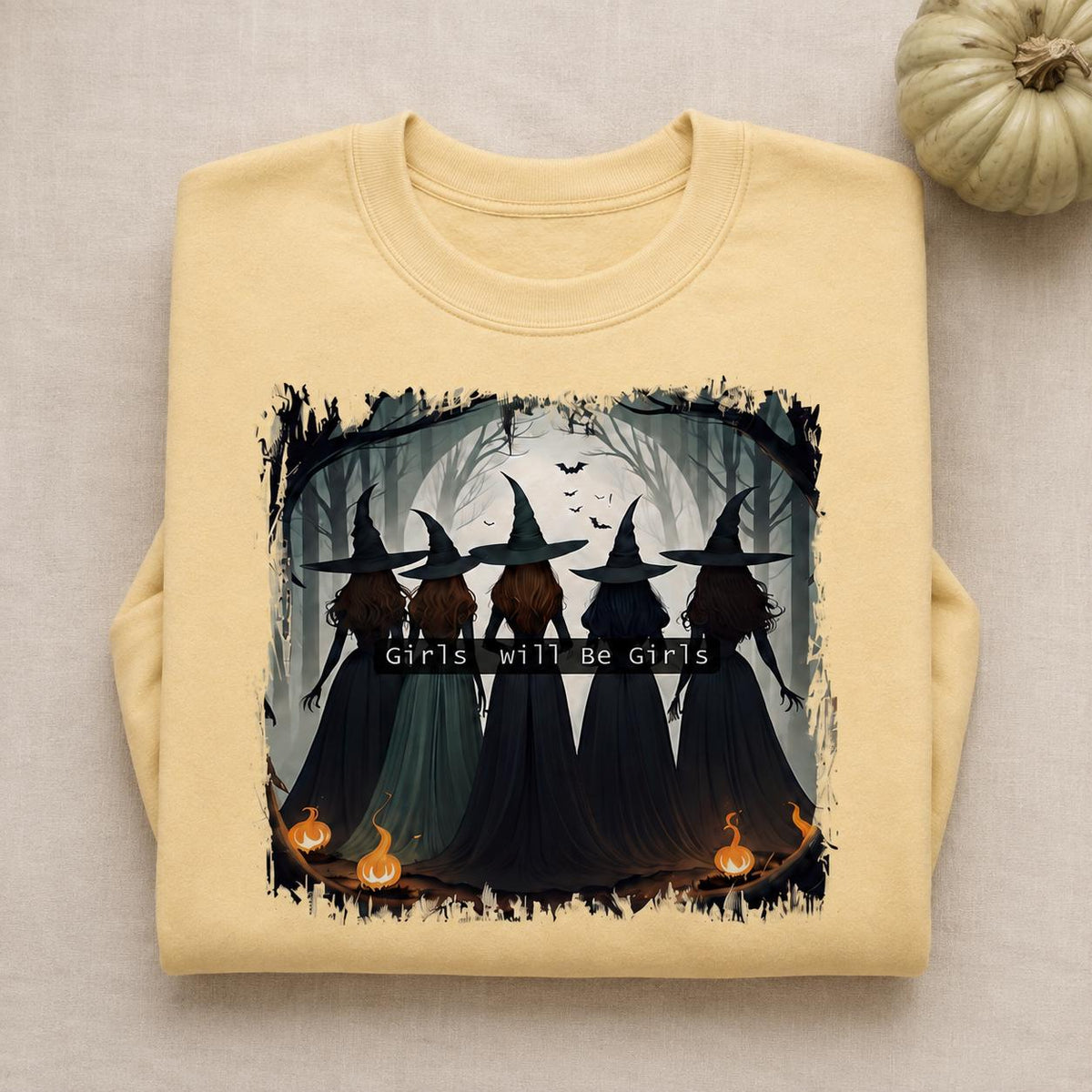 Folded yellow Girls Will Be Girls Witch Sweatshirt with vintage Halloween witch graphic and pumpkin accents

