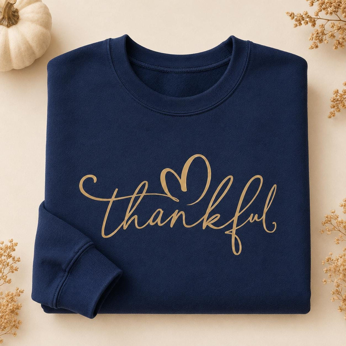 Folded navy Thankful Sweatshirt with gold script heart design and fall floral accents
