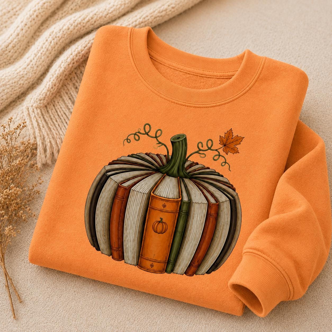 Folded orange Fall Book Lover Sweatshirt with pumpkin-shaped book graphic in a cozy autumn setting
