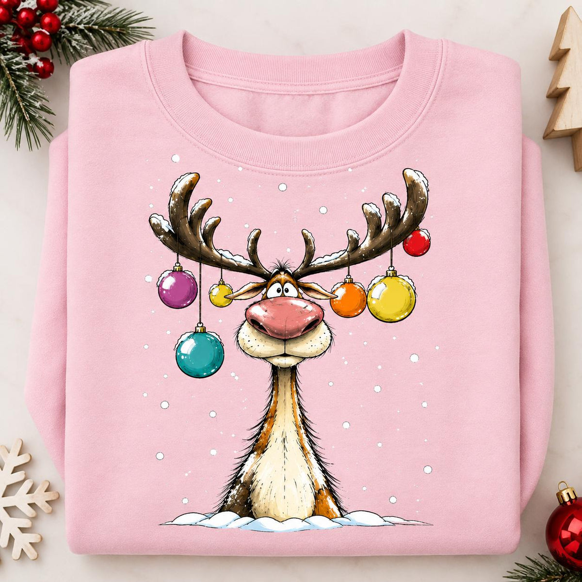 Folded Light Pink Christmas reindeer sweatshirt with colorful ornament antlers.