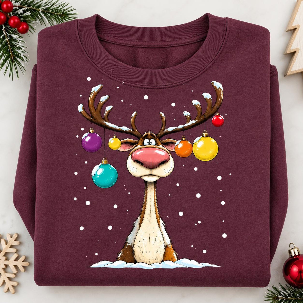 Folded Maroon funny Christmas sweatshirt with decorated reindeer graphic.