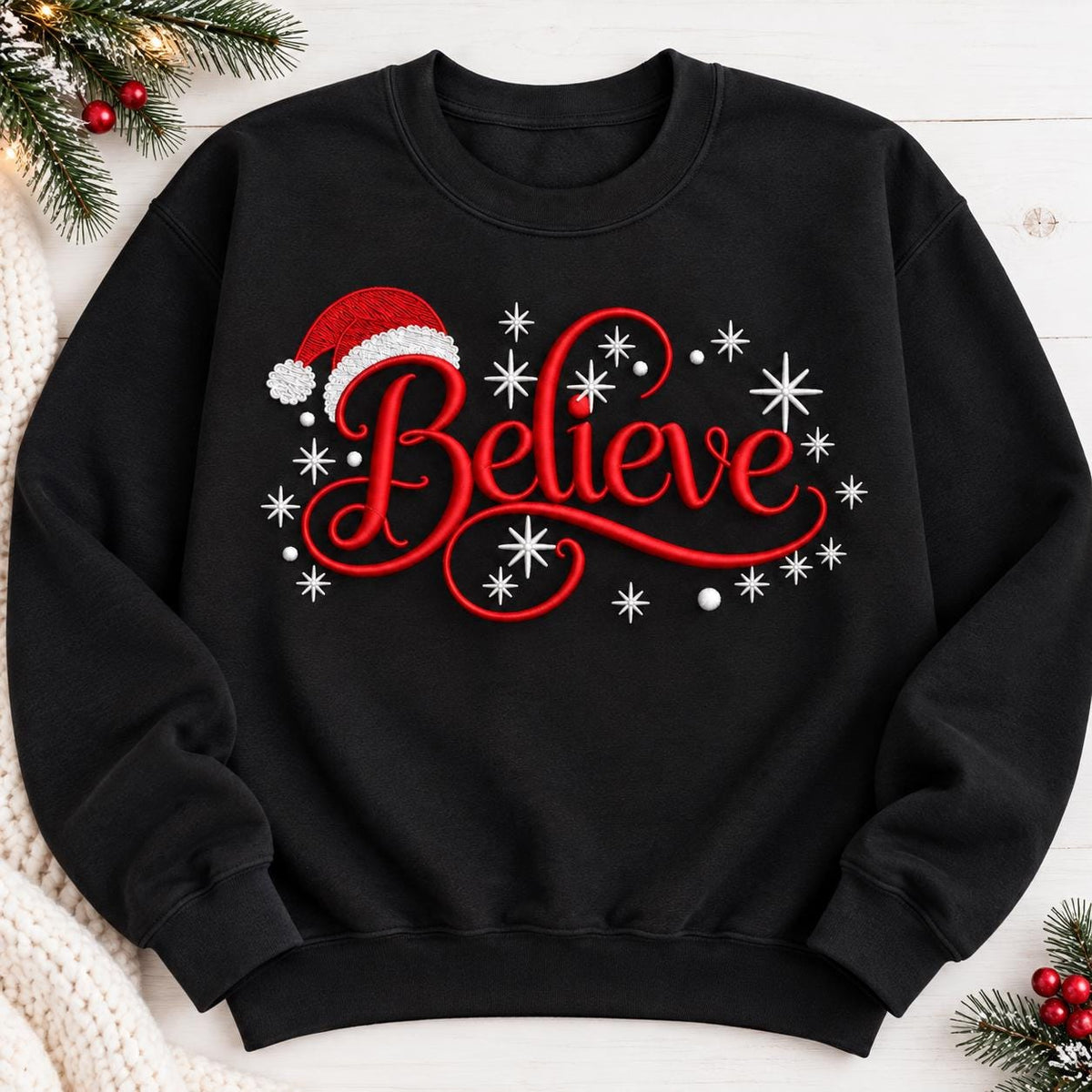 Black Believe Christmas crewneck sweatshirt laid flat with holiday greenery.