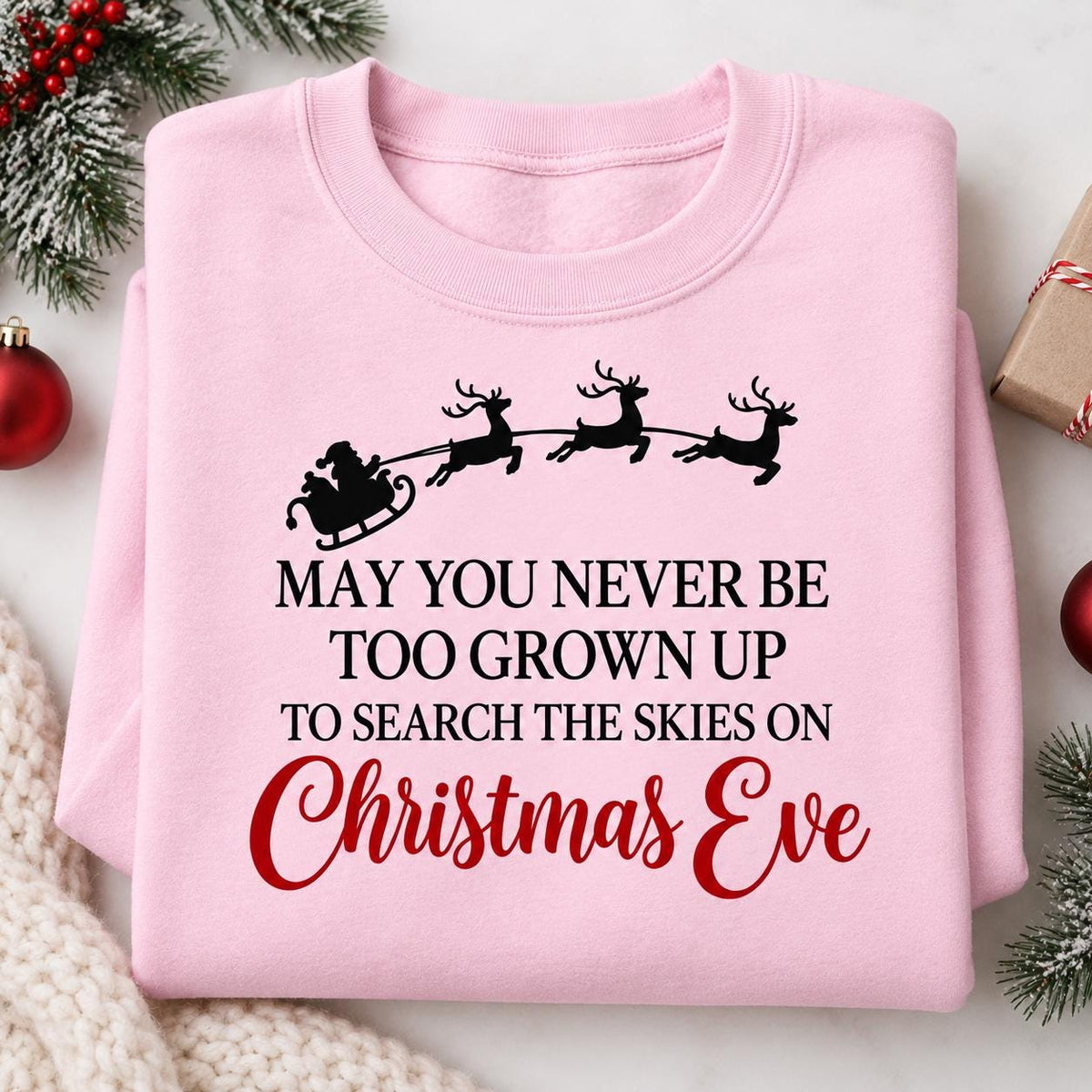 Folded Light Pink Santa sleigh Christmas sweatshirt with black and red lettering.
