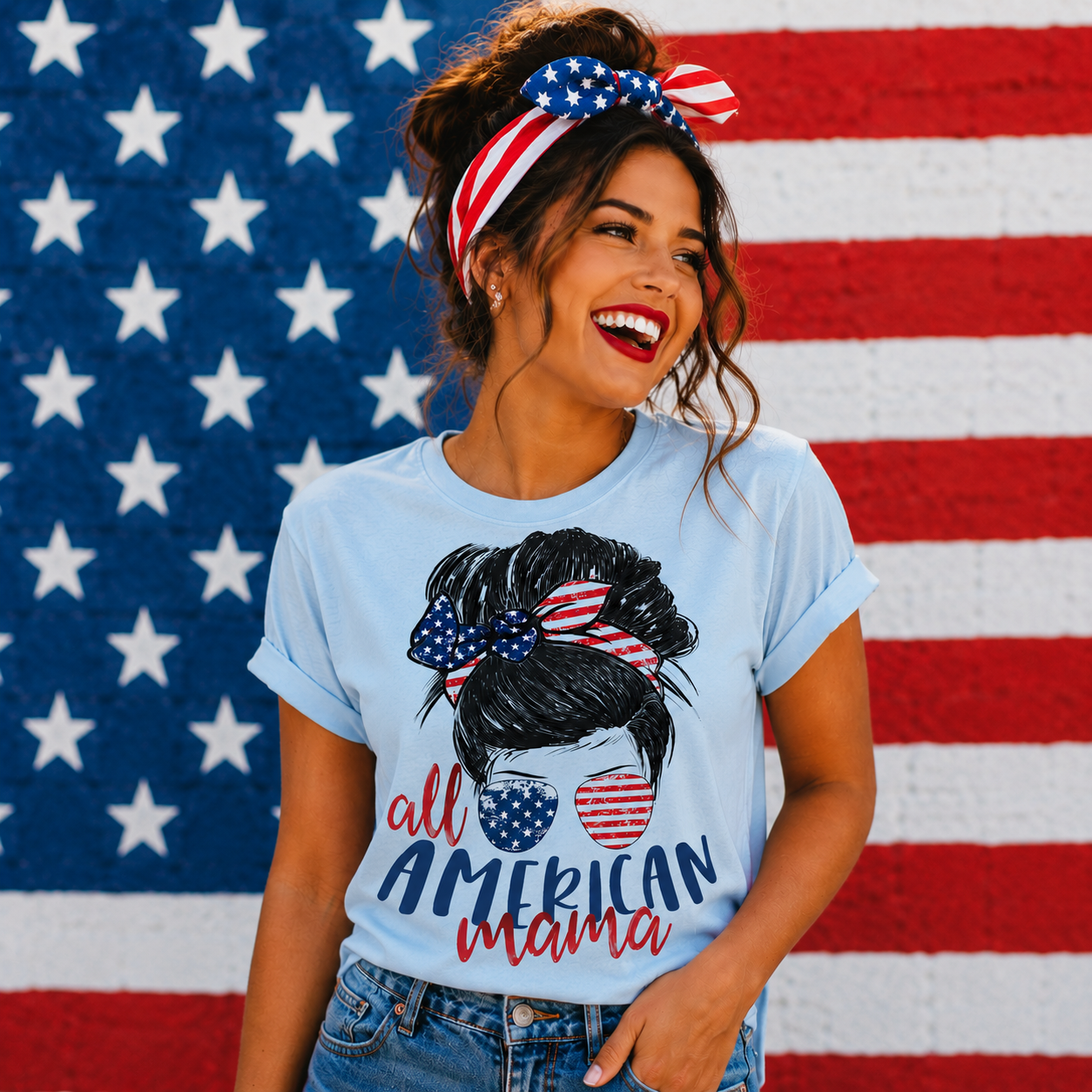 Woman wearing a 'All American Mama' t-shirt with an American flag headband in front of an American flag background.