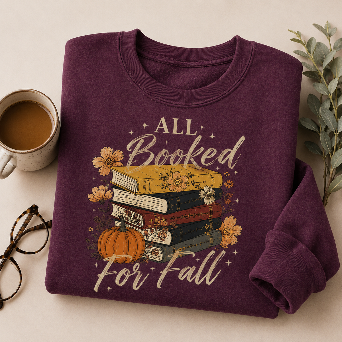 Folded Maroon Fall Book Lover Sweatshirt with All Booked for Fall books and pumpkin graphic, styled with coffee and reading glasses.