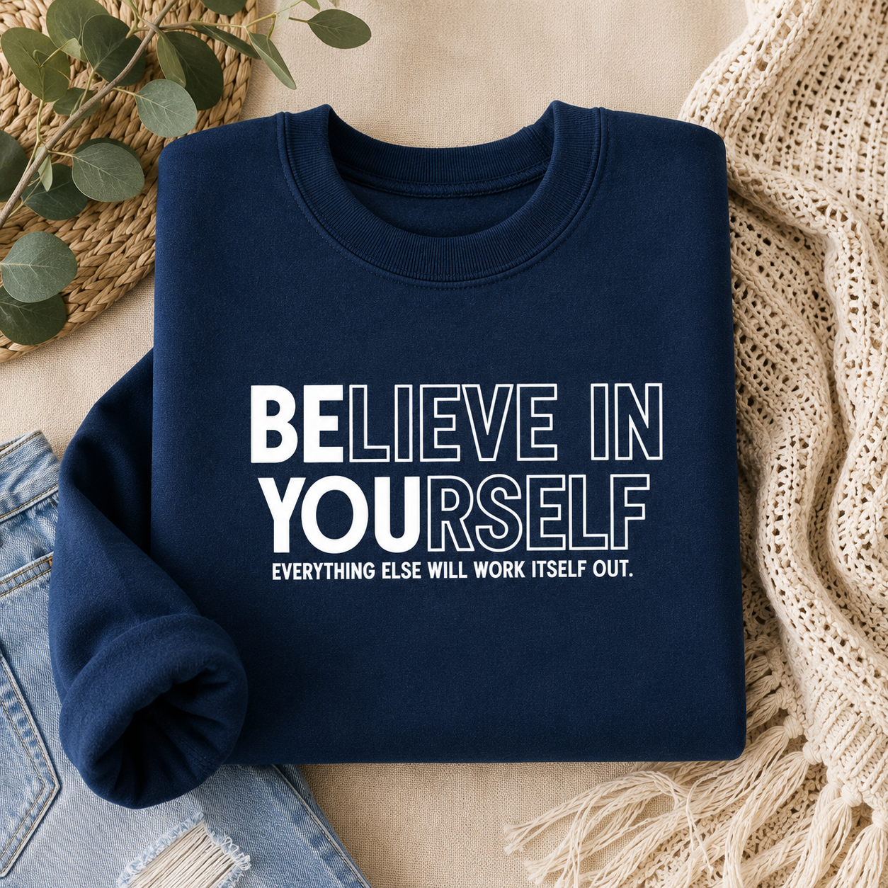 A navy blue crewneck sweatshirt with the motivational text 'BELIEVE IN YOURSELF. EVERYTHING ELSE WILL WORK ITSELF OUT.