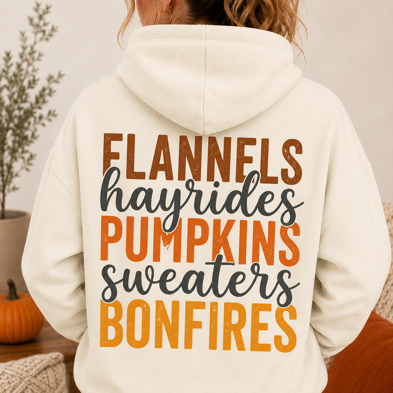 Woman wearing an Off White fall hoodie with Flannels, Hayrides, Pumpkins, Sweaters and Bonfires graphic printed on the back.