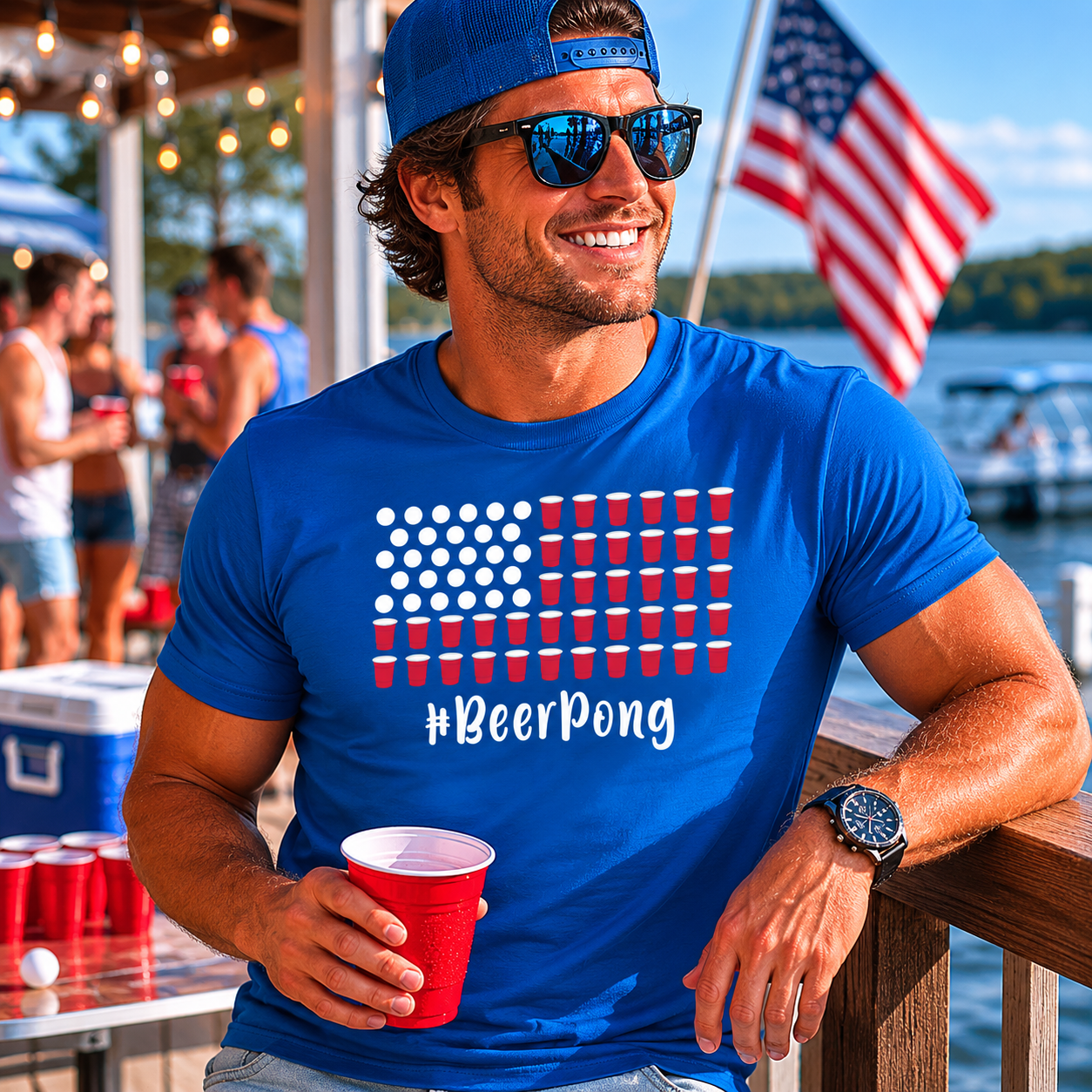 Man wearing a blue '#BeerPong' t-shirt by a lake with American flag in background
