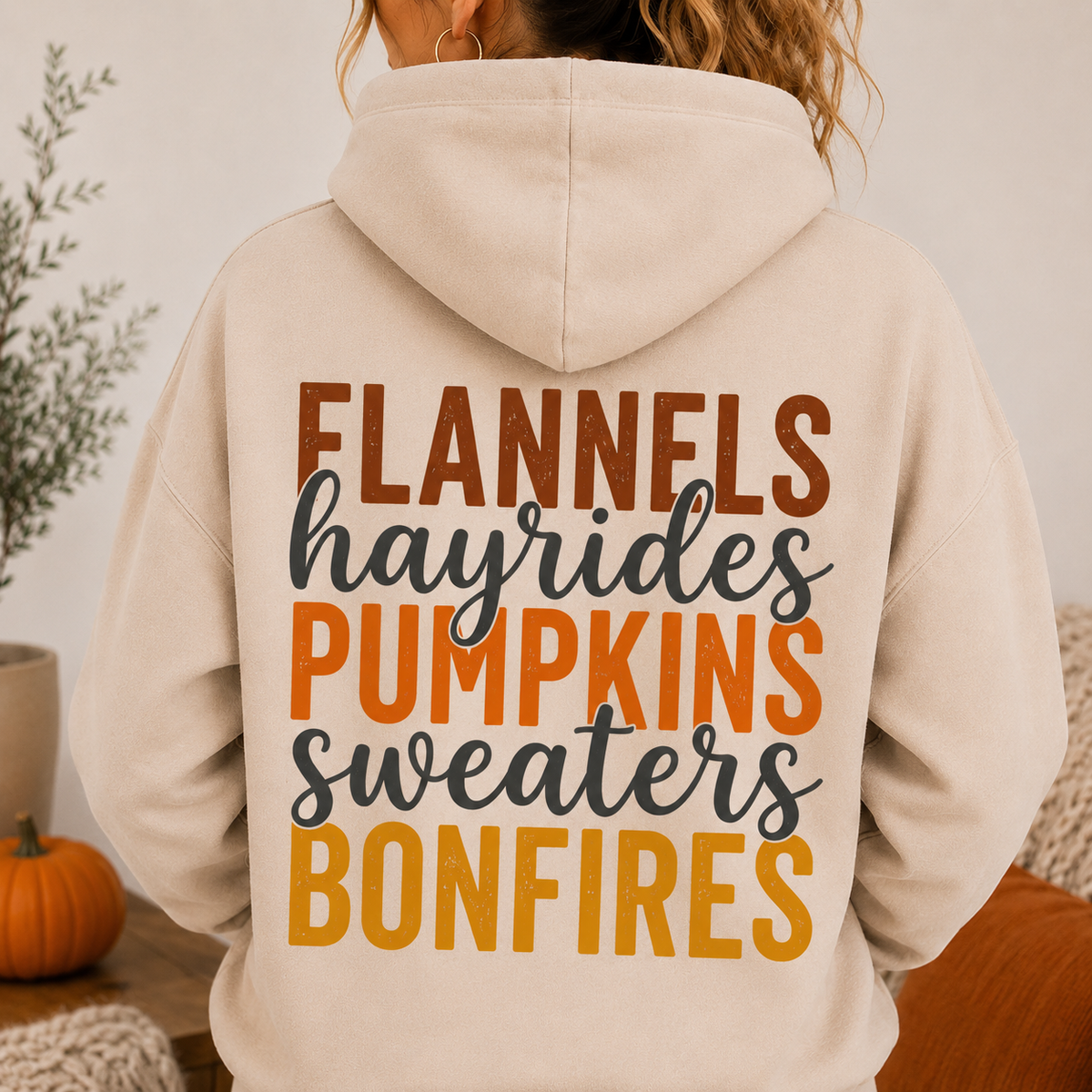 Woman wearing a Sand fall hoodie with Flannels, Hayrides, Pumpkins, Sweaters and Bonfires graphic printed on the back.