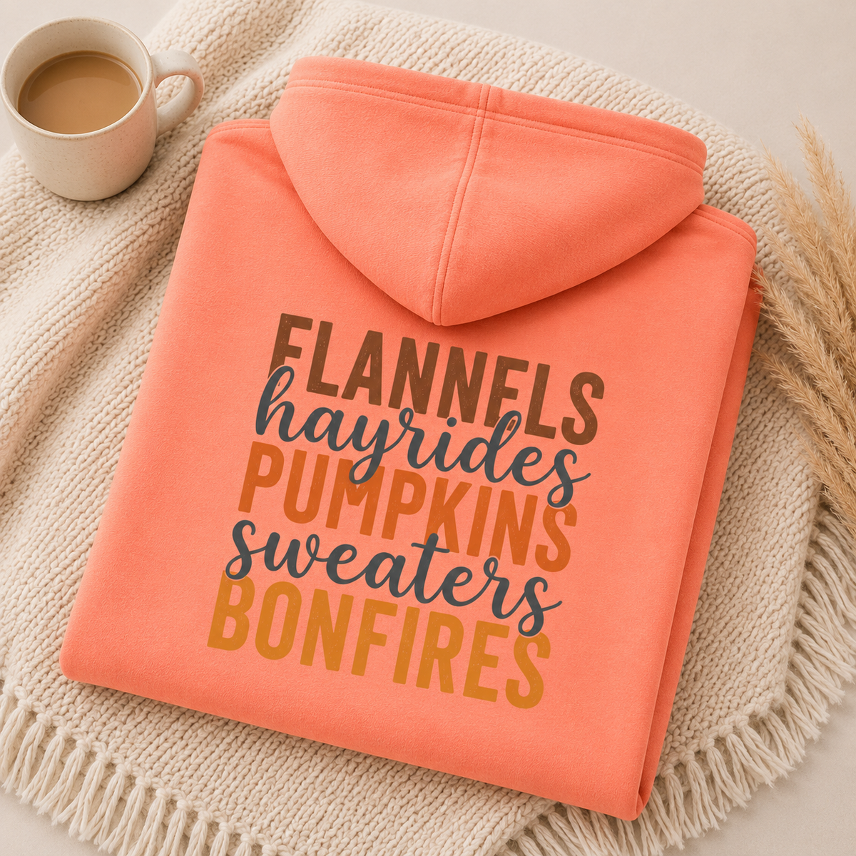Folded Tangerine fall hoodie with Flannels, Hayrides, Pumpkins, Sweaters and Bonfires graphic printed on the back.